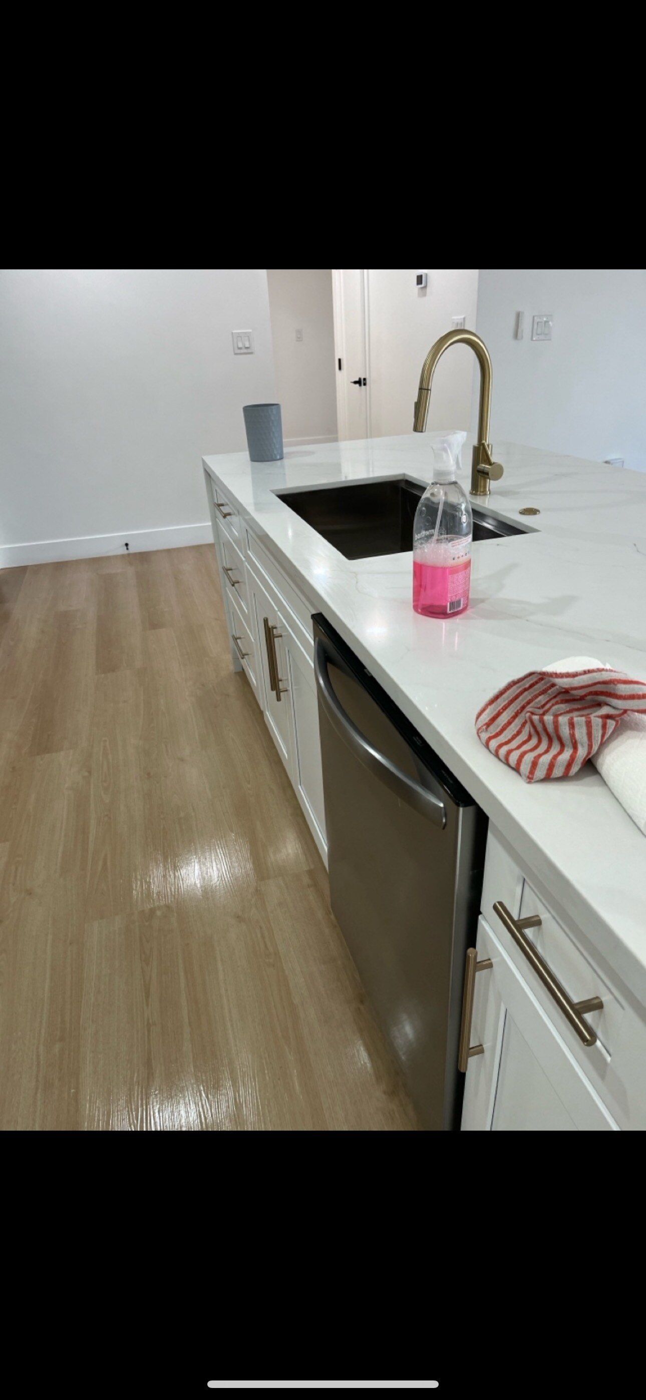 A kitchen with a sink , dishwasher , and towel on the counter.
