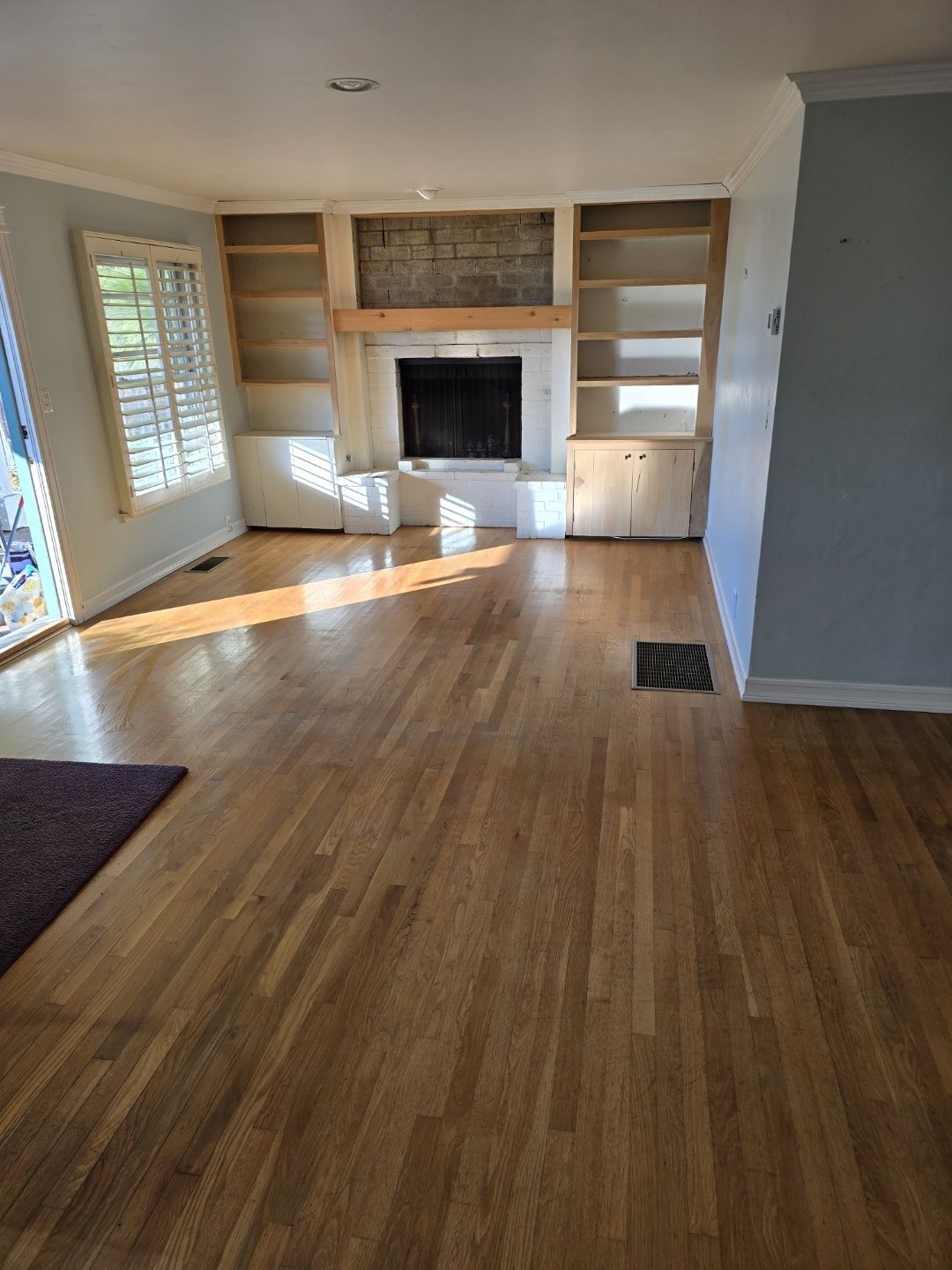 An empty living room with hardwood floors and a fireplace.
