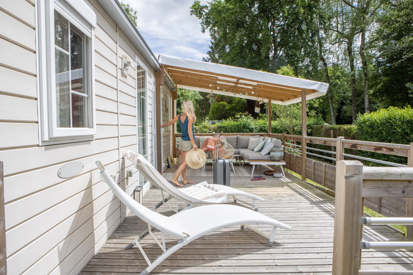 A woman is standing on the deck of a mobile home.