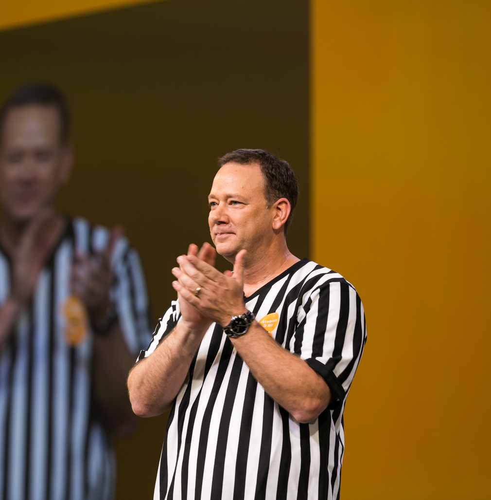 A man in a black and white striped shirt is clapping his hands.