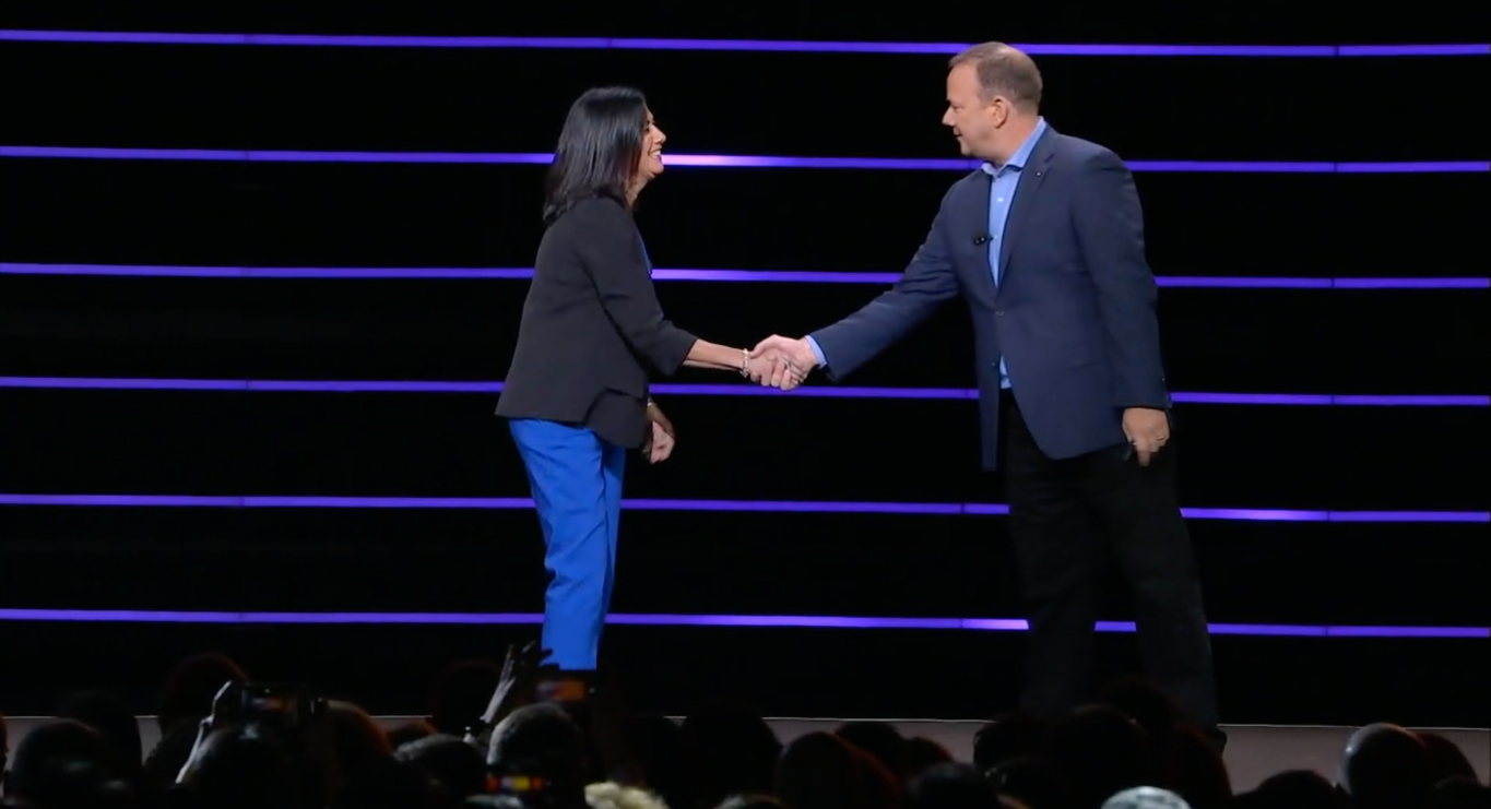 A man and a woman are shaking hands on a stage.