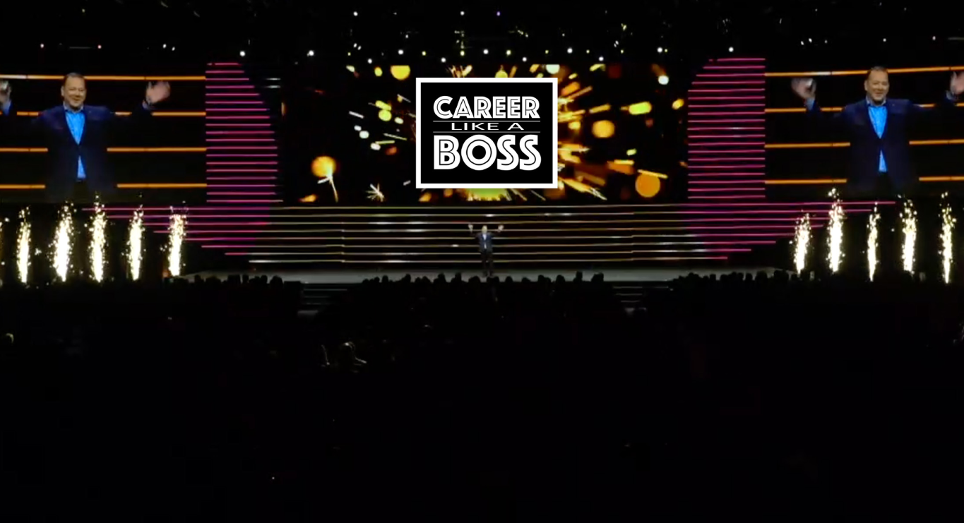 A man is standing on a stage with a sign that says career boss looking at the crowd.