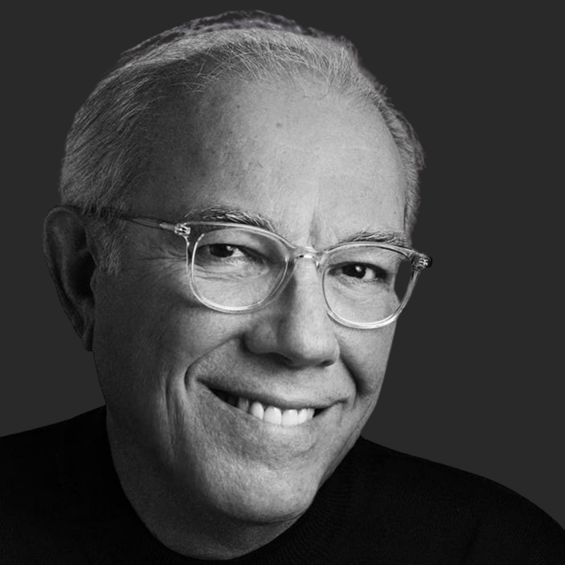 A man wearing glasses is smiling in a black and white photo.