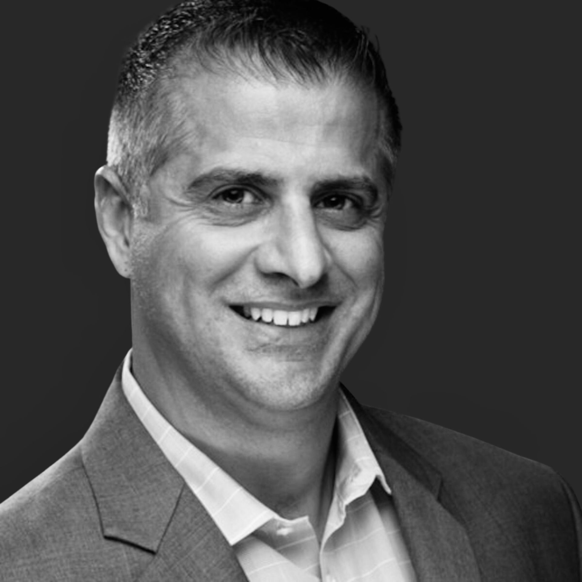 A man in a suit and white shirt is smiling in a black and white photo.