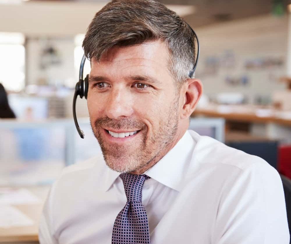 A man in a white shirt and tie is wearing a headset.