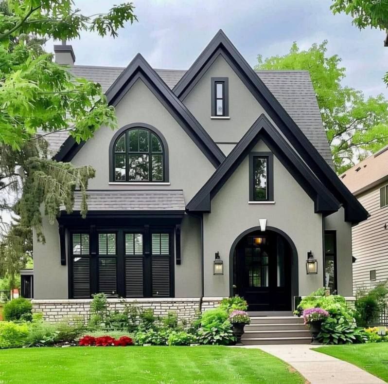 Gray house with black trim, arched doorway, and lush landscaping.