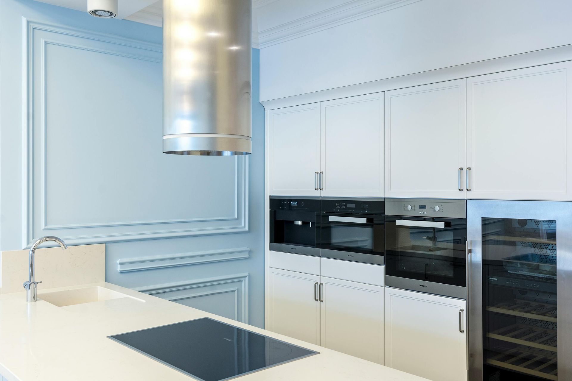 Modern white kitchen with stainless steel appliances, countertop, and cabinets.