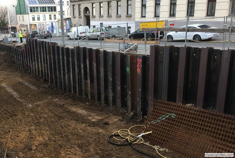 ein Metallzaun auf einer Baustelle mit Autos dahinter .