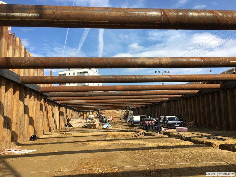 eine Baustelle mit vielen rostigen Metallrohren und einer Holzwand .