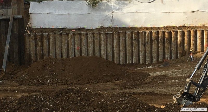 Auf einer Baustelle steht ein Bagger neben einem Haufen Erde .