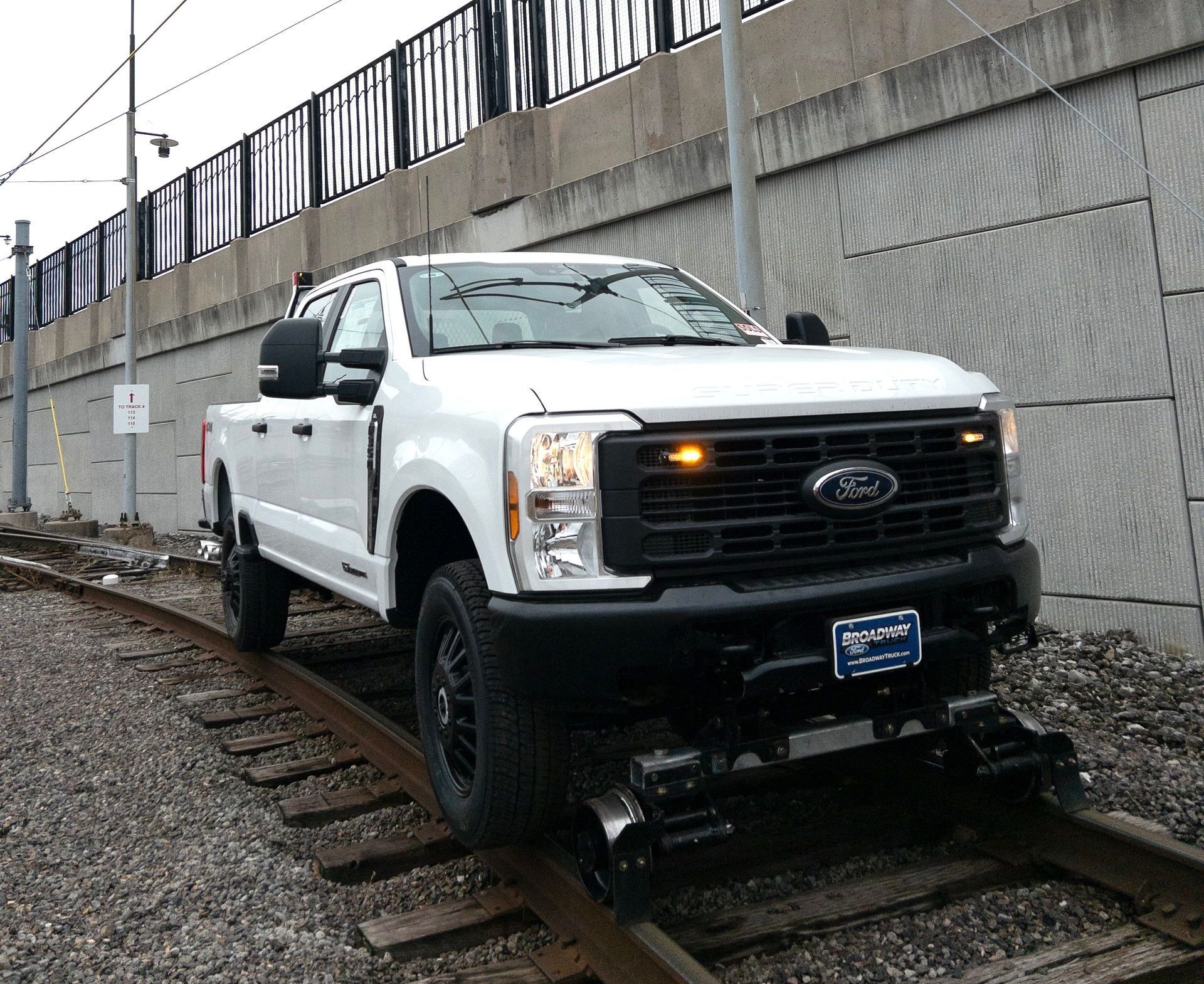 White Ford truck on railroad tracks.