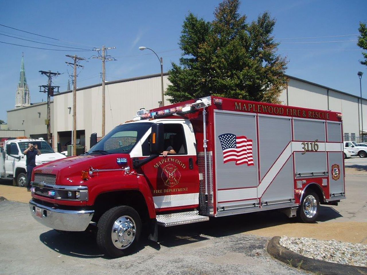 Red and silver fire/rescue truck with American flag on the side, parked on a street.
