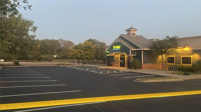 Restaurant building with a gray exterior, parking lot, and trees in the background.