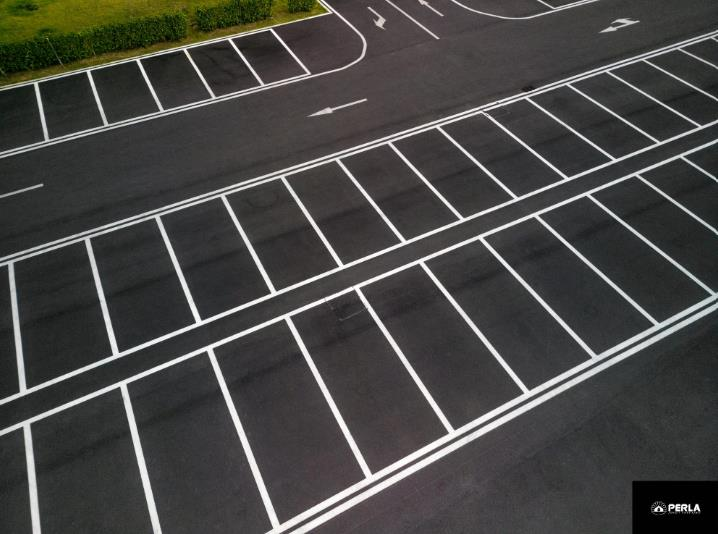 Aerial view of an asphalt parking lot with white painted parking space lines.