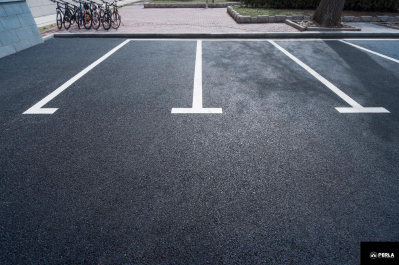 Empty parking spaces with white lines on asphalt; bicycles visible in the background.
