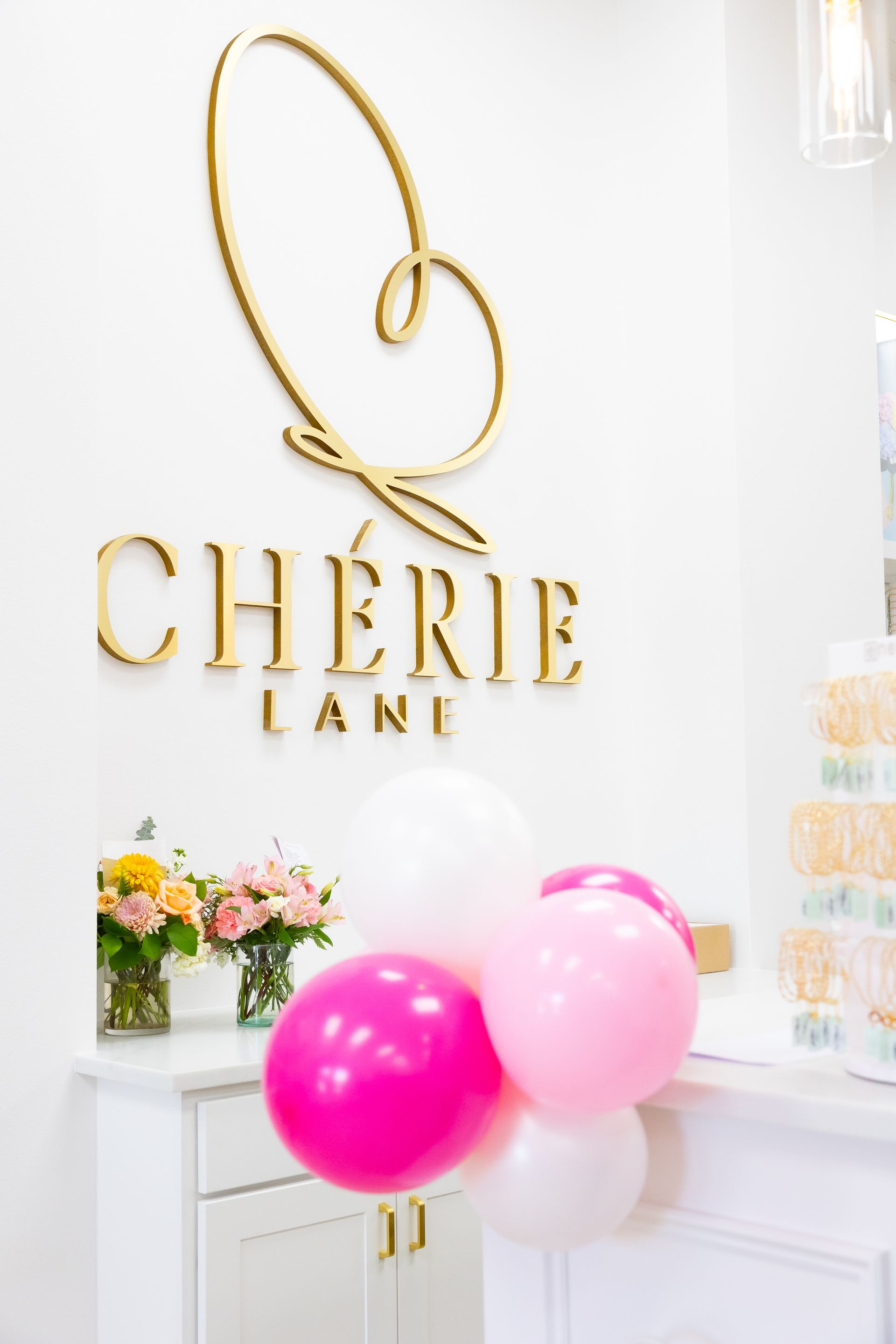 Woman in white dress and boots pushing a green shopping cart filled with shiny silver disco balls.