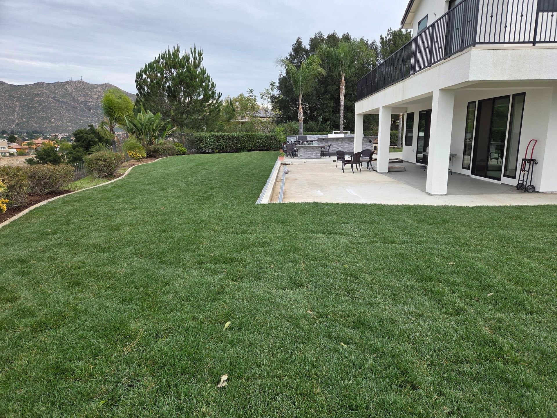 Elegant house with fountain and palm trees in gravel yard.