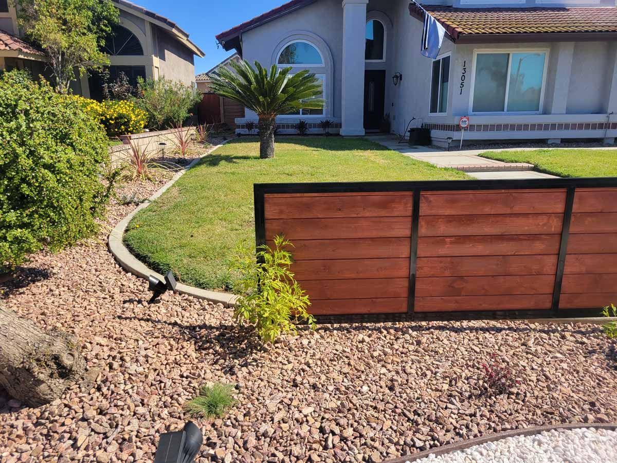 Front yard with house, lawn, rock landscaping, and a wooden fence.
