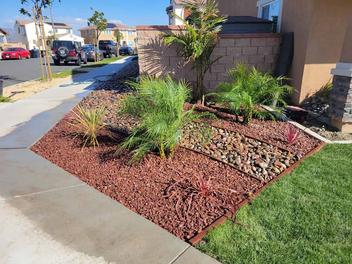 Landscaped yard with red mulch, plants, and decorative rocks.