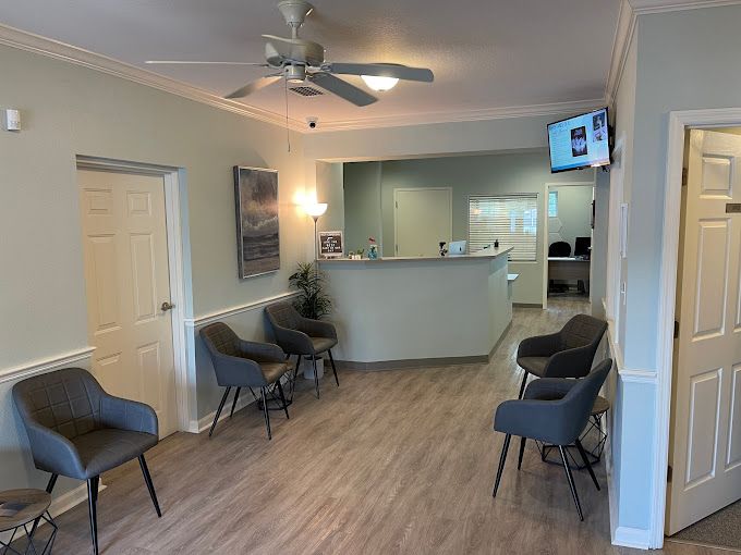 A waiting room with chairs and a ceiling fan.