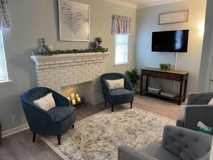 A living room with two chairs , a fireplace and a flat screen tv.