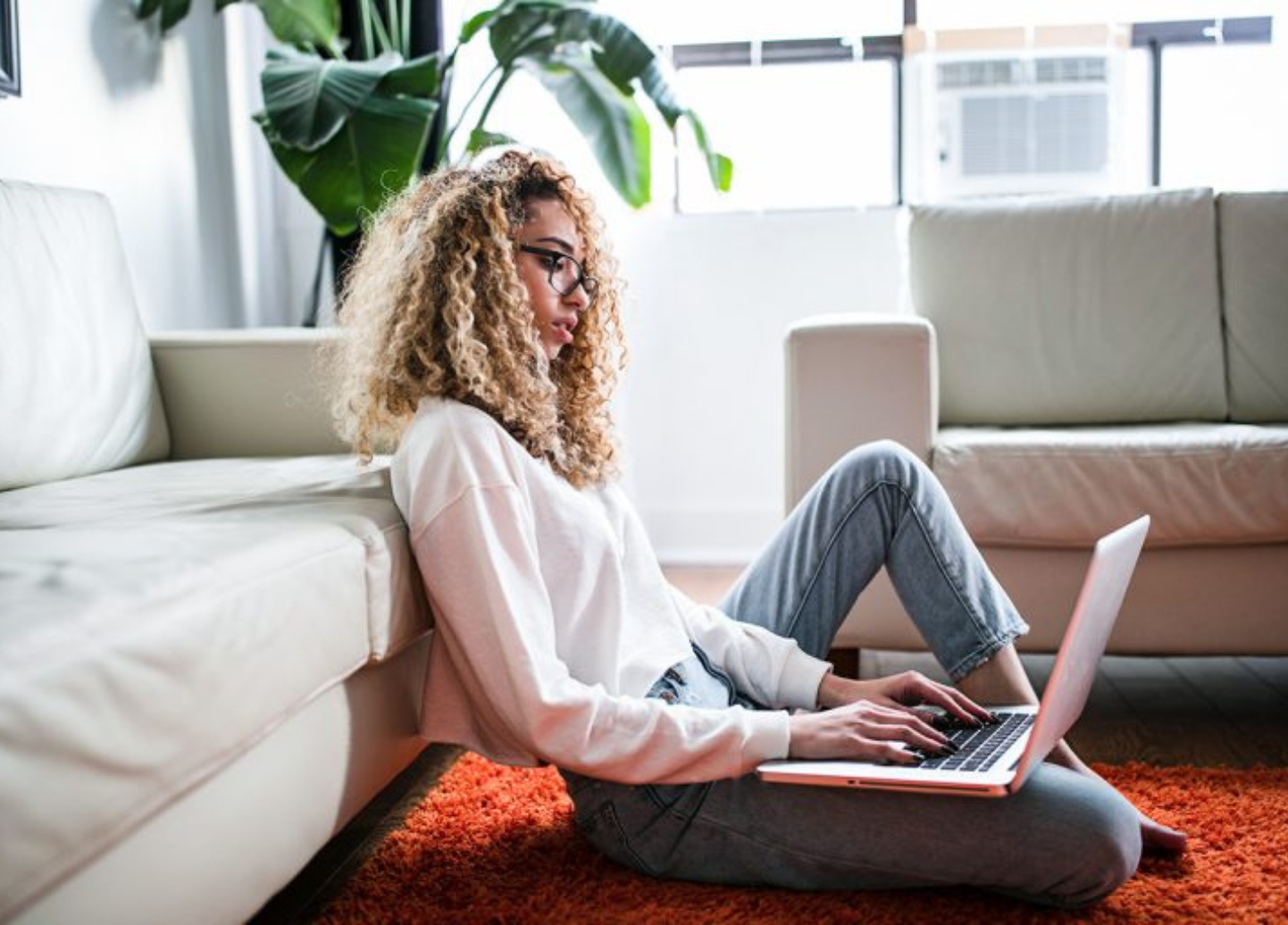 A woman is sitting on the floor using a laptop computer.