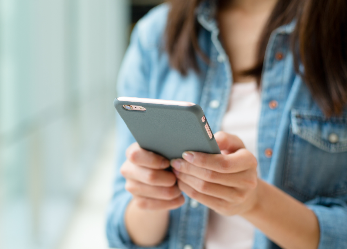 A woman is holding a cell phone in her hands.