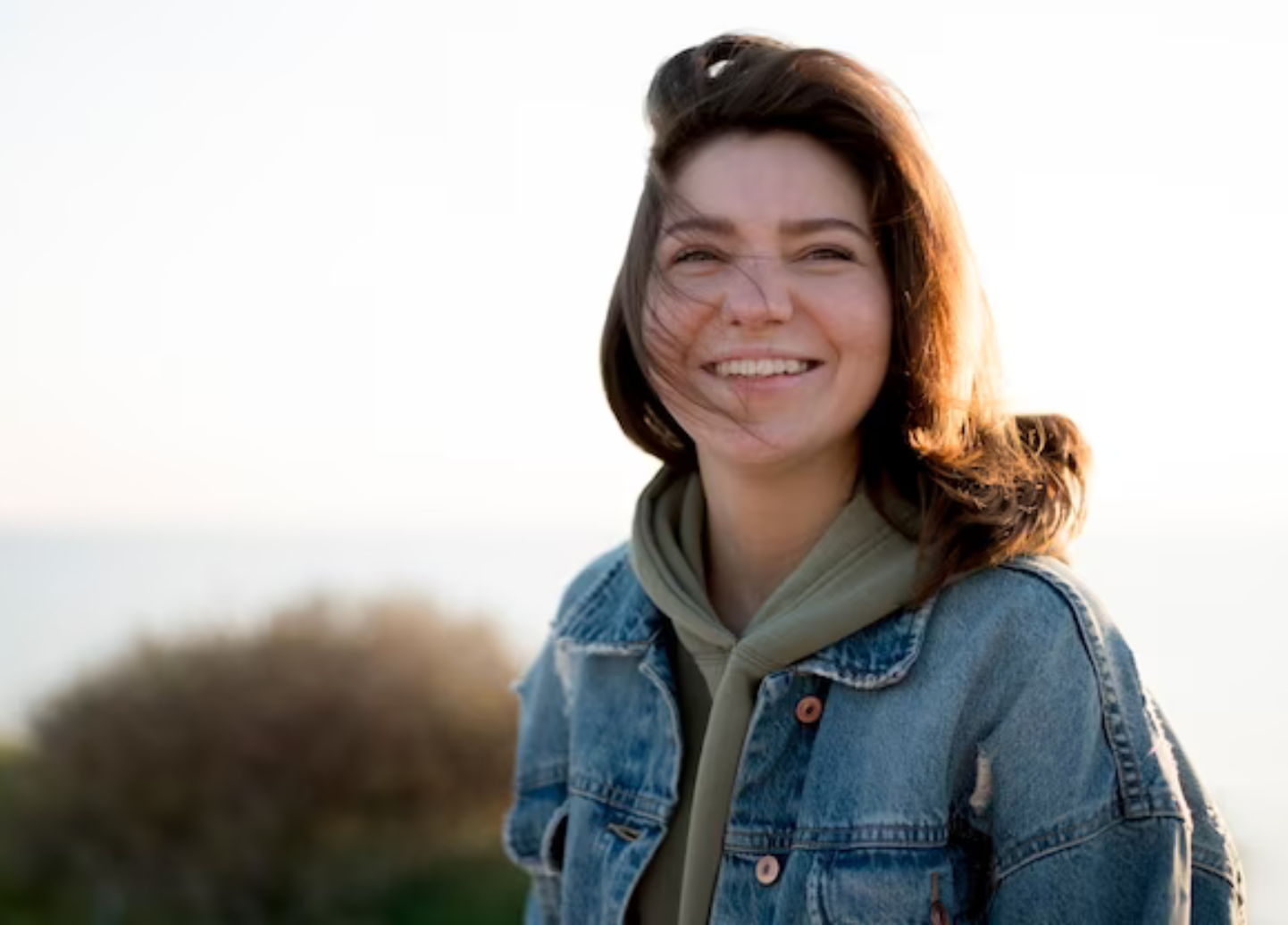 A woman in a denim jacket is smiling for the camera.