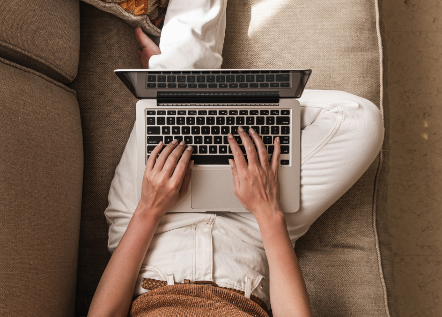 A woman is sitting on a couch using a laptop computer.