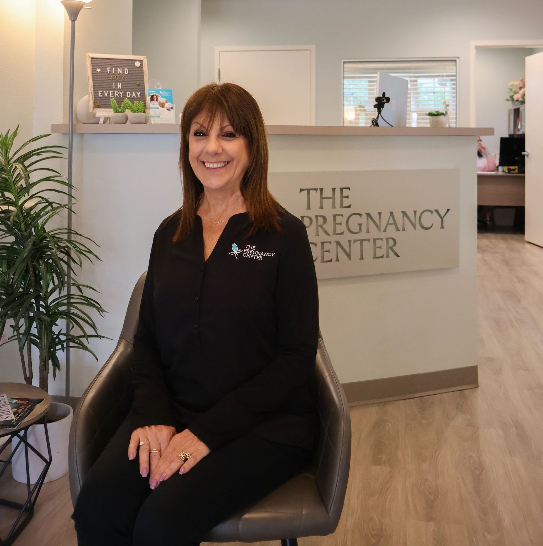 A woman is sitting in front of a sign that says the pregnancy center