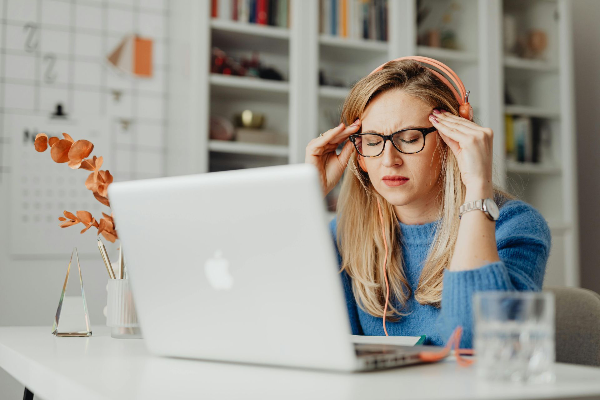 A woman wearing headphones is sitting in front of a laptop computer.