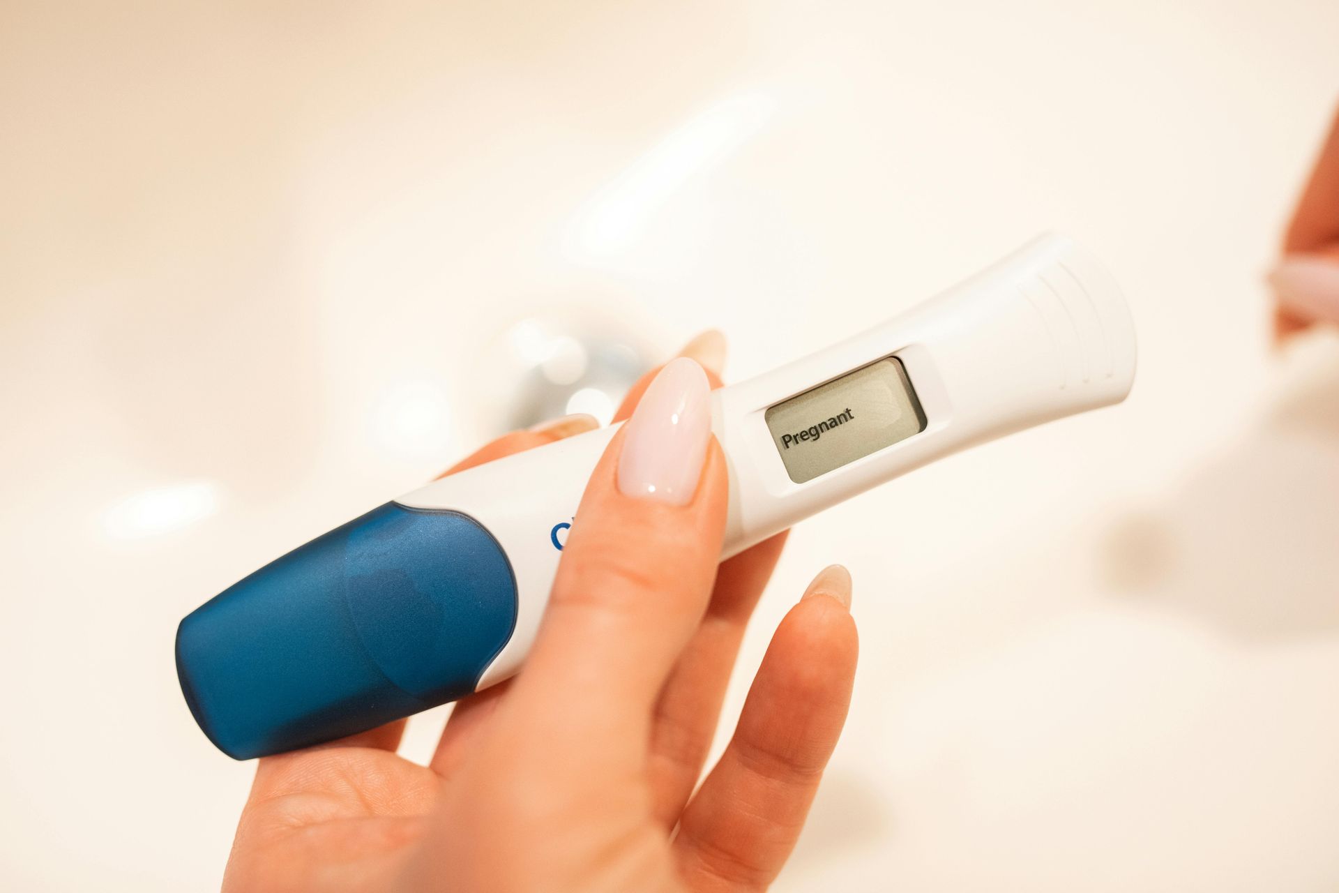 A woman is holding a pregnancy test in her hand.