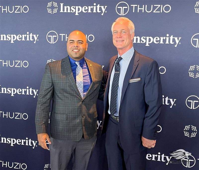 Two men are posing for a picture in front of a wall that says insperity