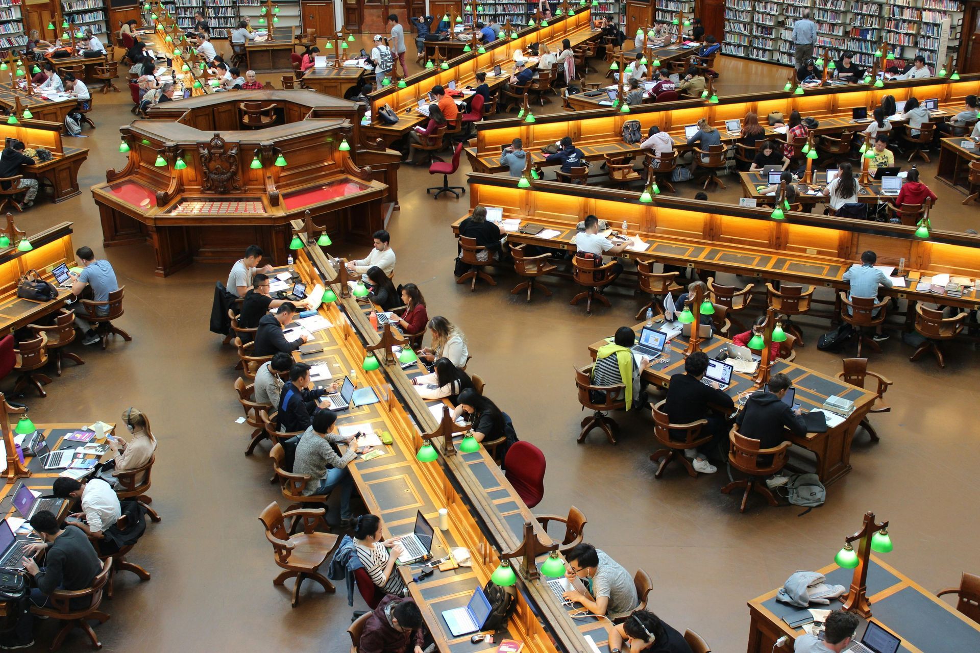 A large group of people are sitting at tables in a library.