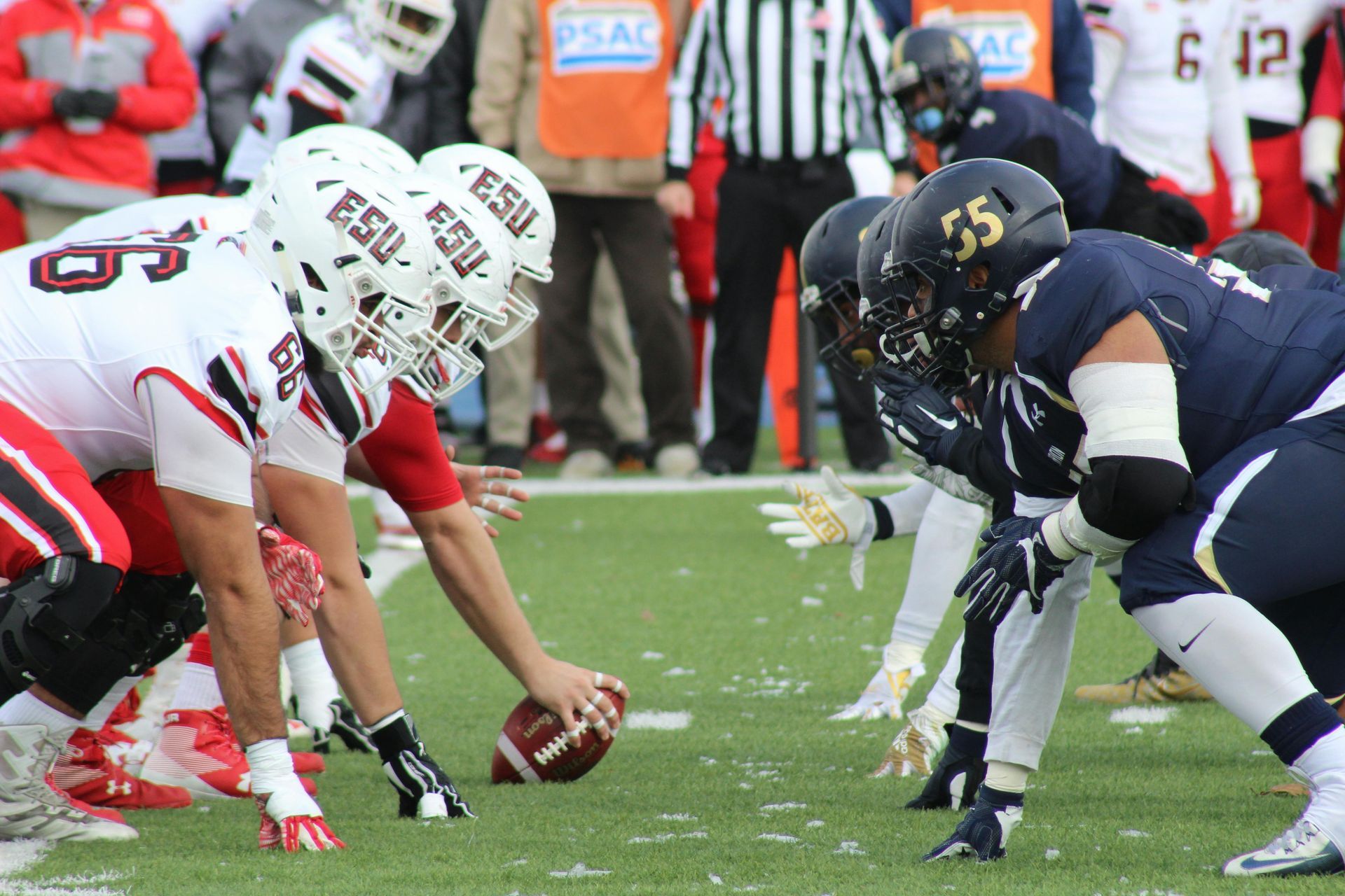 A group of football players wearing esu helmets are lined up on the field