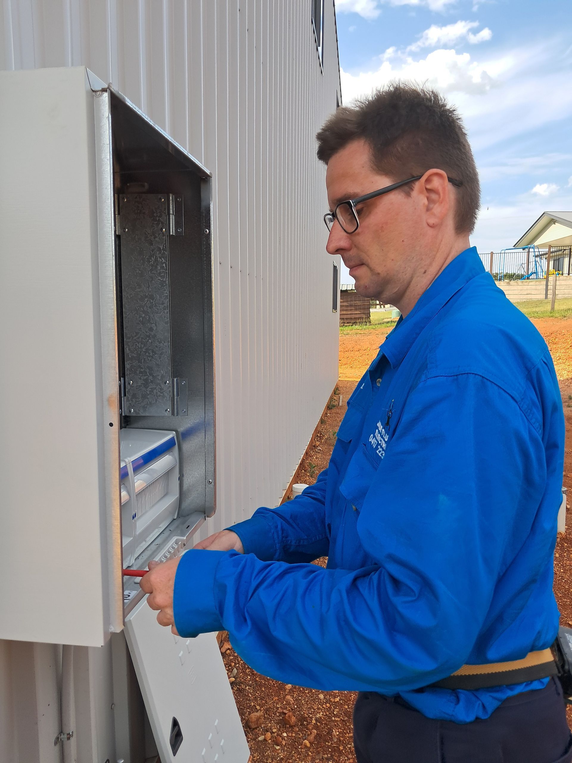 Man in blue uniform working on an electrical box outside. — Jade Fluerty Electrical In Tinana, QLD