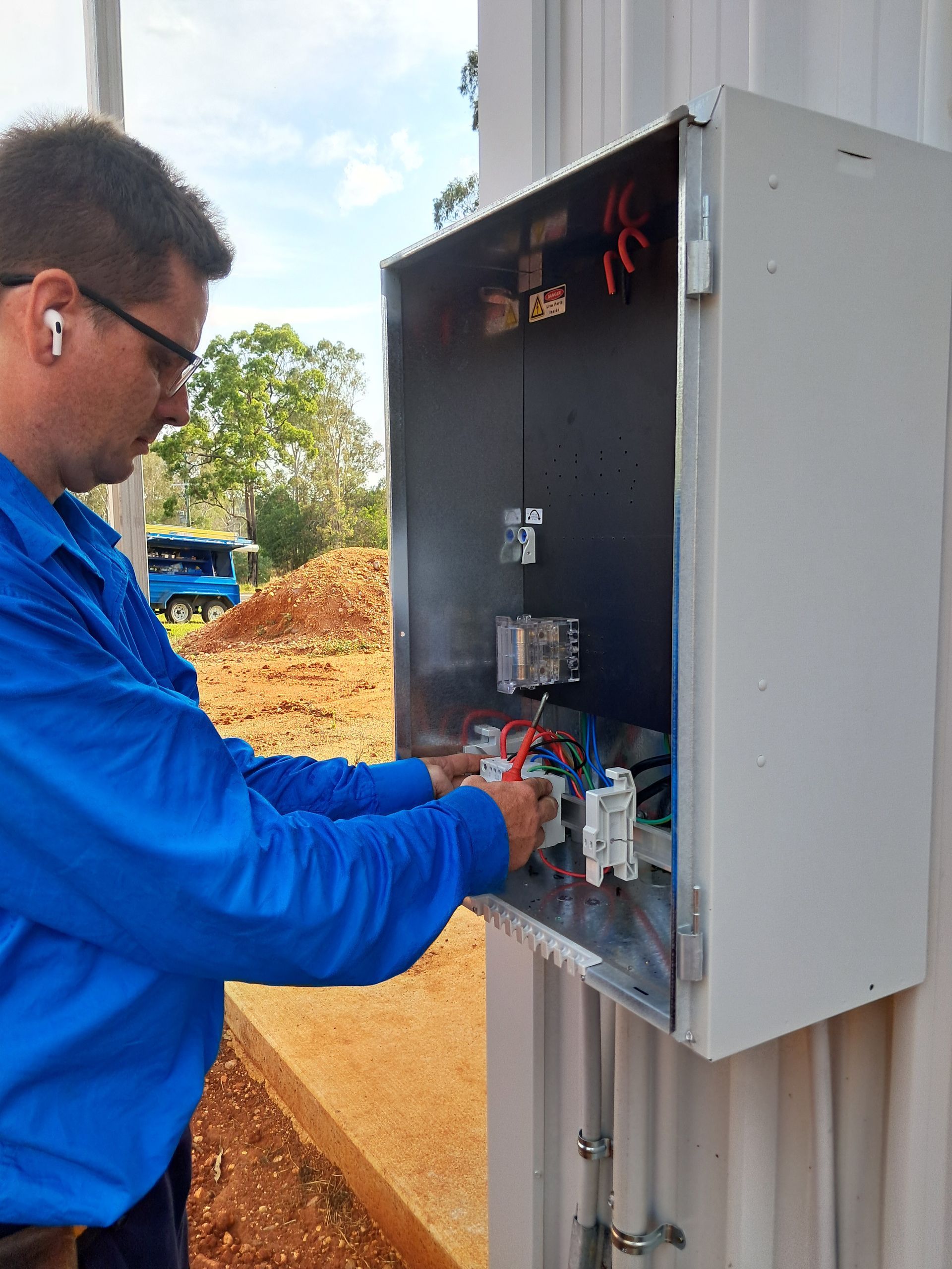 Electrician working on electrical panel outdoors. — Jade Fluerty Electrical In Tinana, QLD