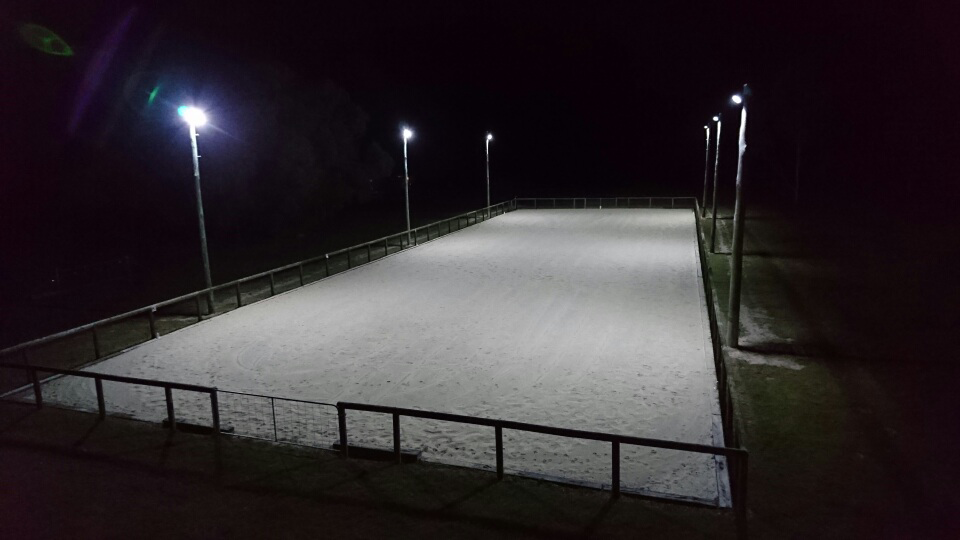 An illuminated equestrian arena at night, surrounded by fencing and light poles, with a dark sky — Jade Fluerty Electrical In Tinana, QLD