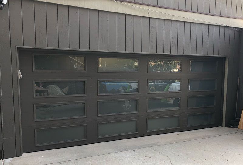 A wooden garage door with blue trim and windows