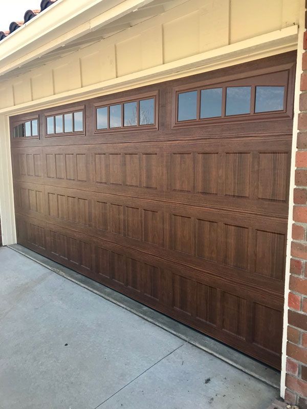 A wooden garage door with blue trim and windows