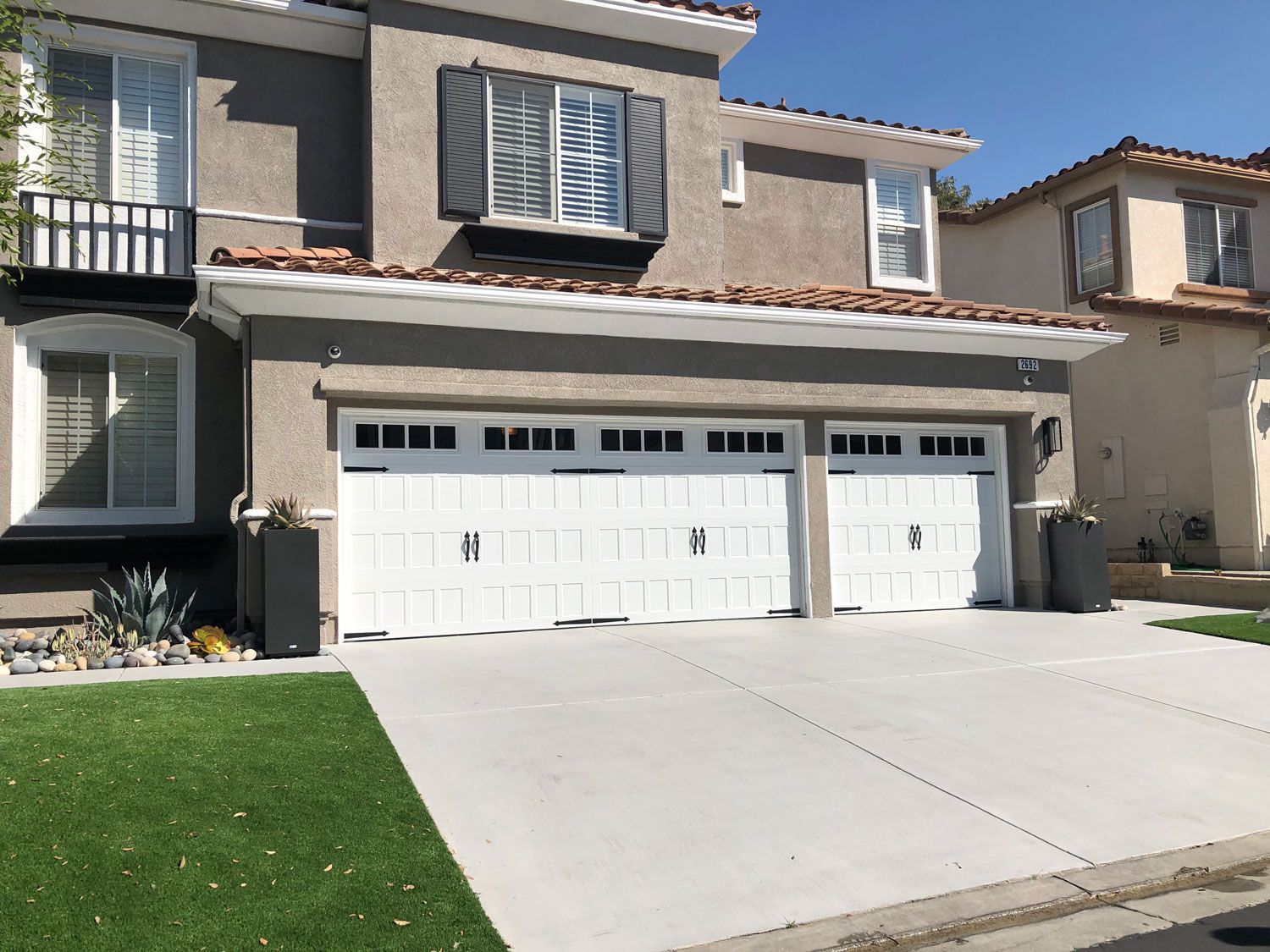 A black garage door with frosted glass is sitting on a concrete driveway.