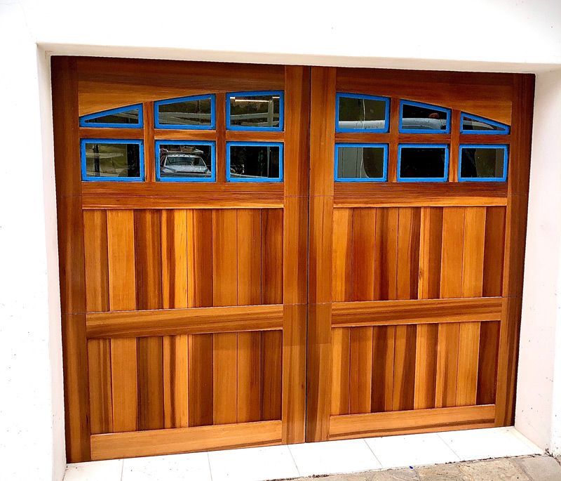 A wooden garage door with blue trim and windows