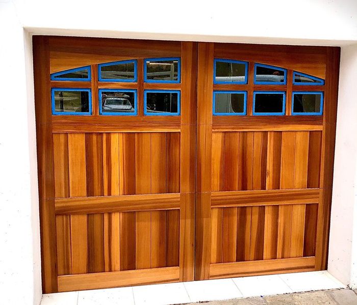 A wooden garage door with blue trim and windows