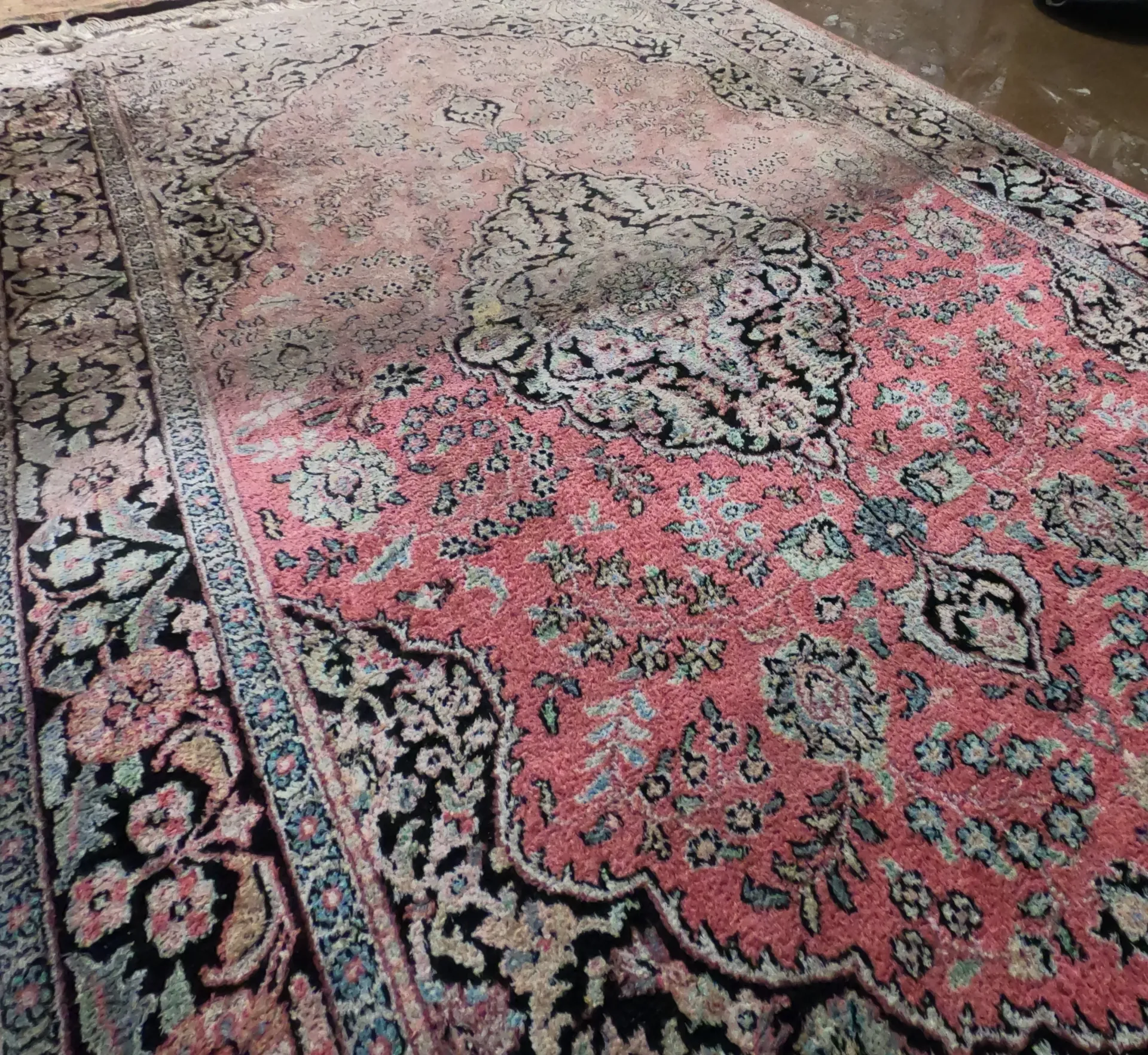 A pink rug with a floral pattern is sitting on a wooden floor.