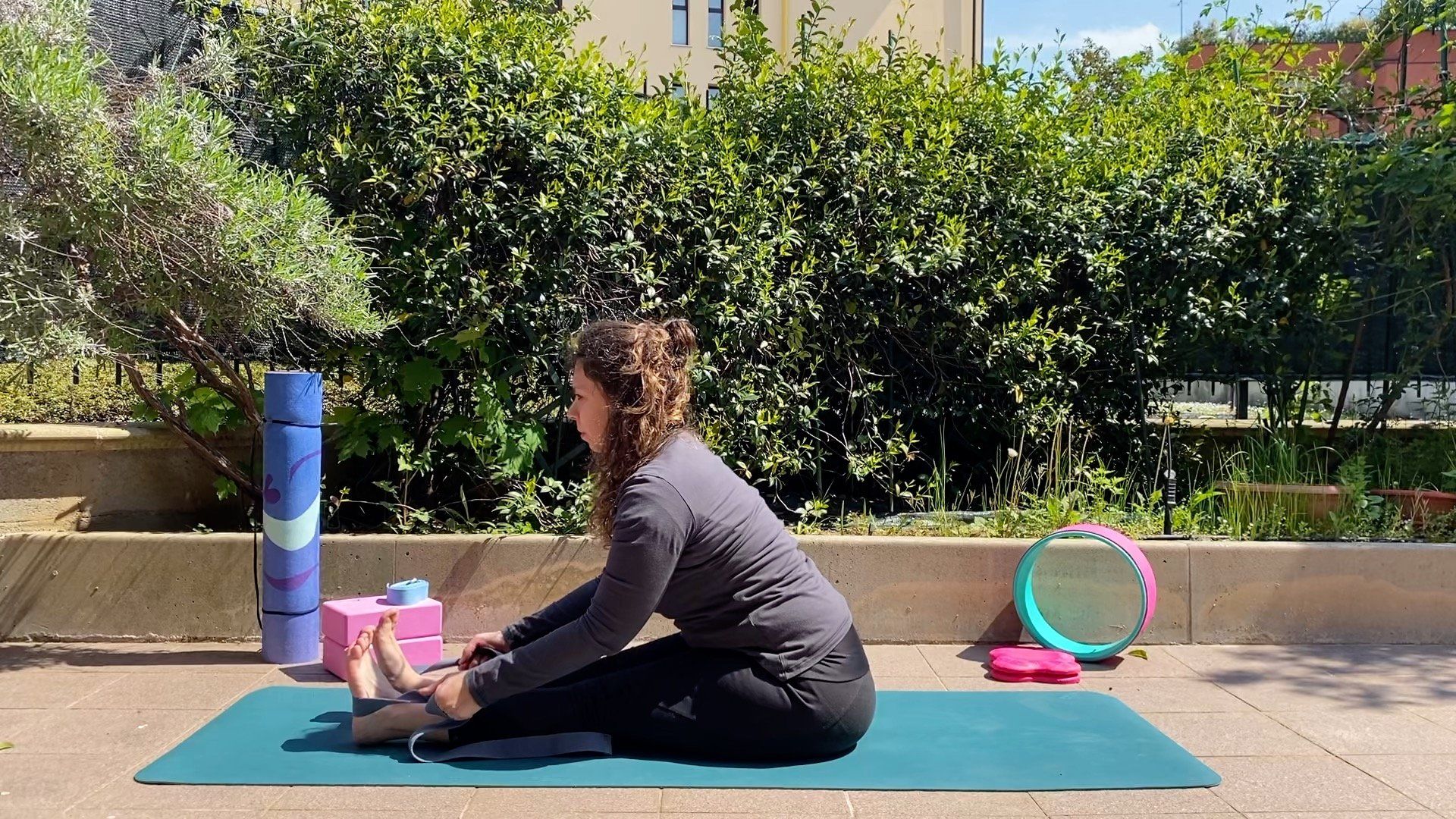 Ragazza in tuta fitness seduta su tappetino per fare yoga