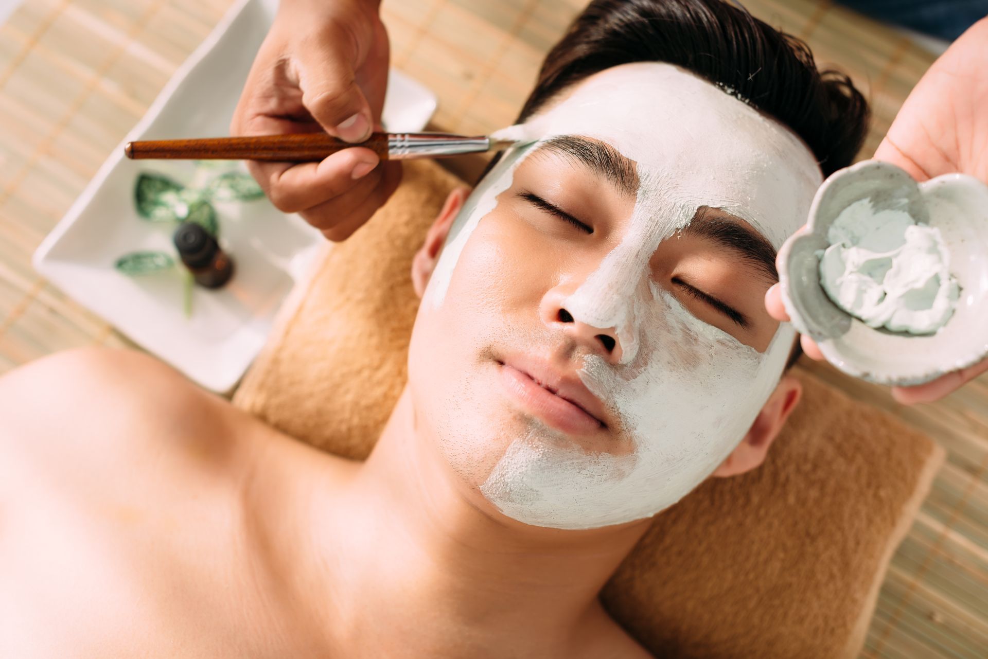 a man is getting a white mask on his face at a spa .