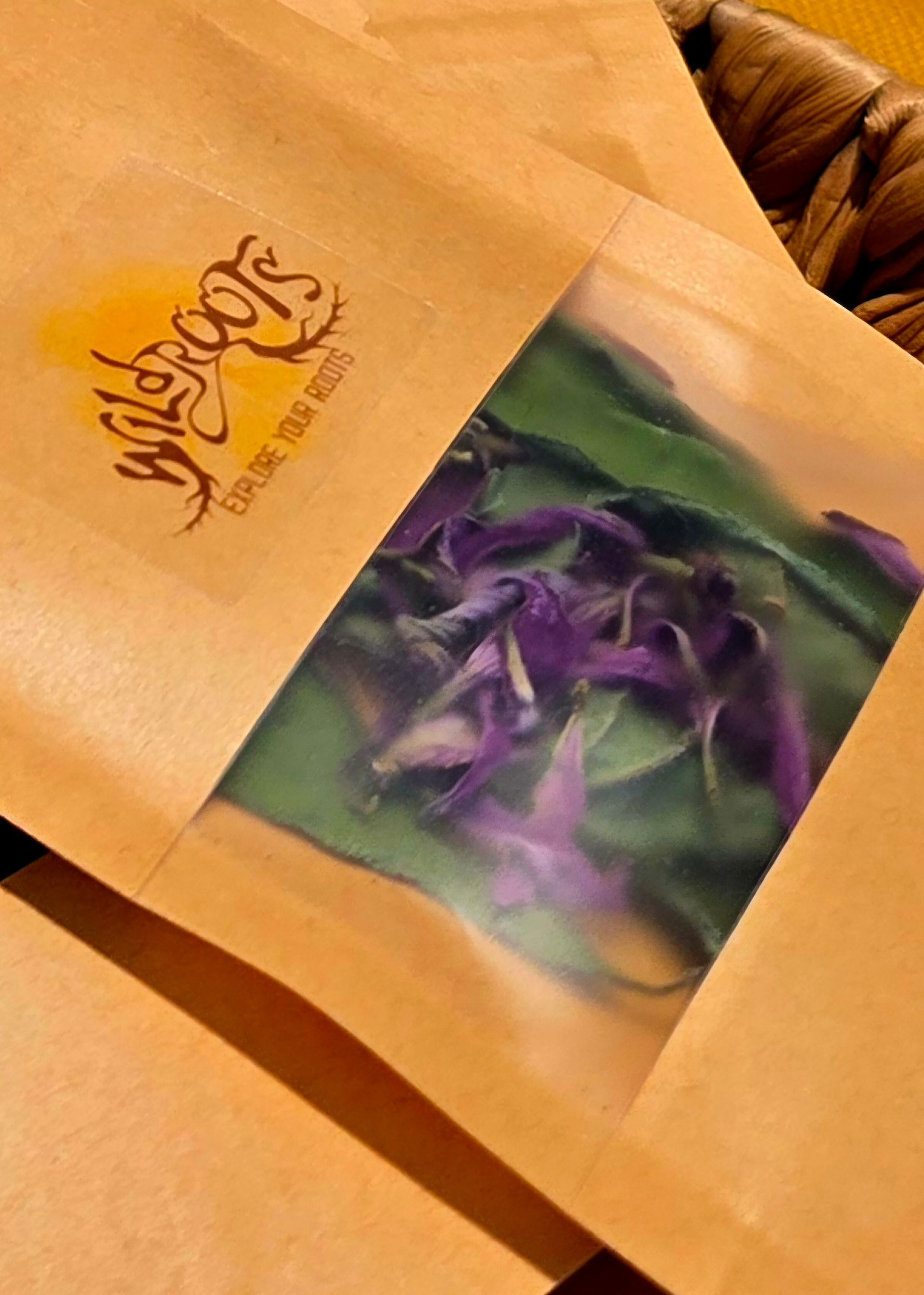 Brown paper bags with clear window, showing purple flower petals and green leaves.