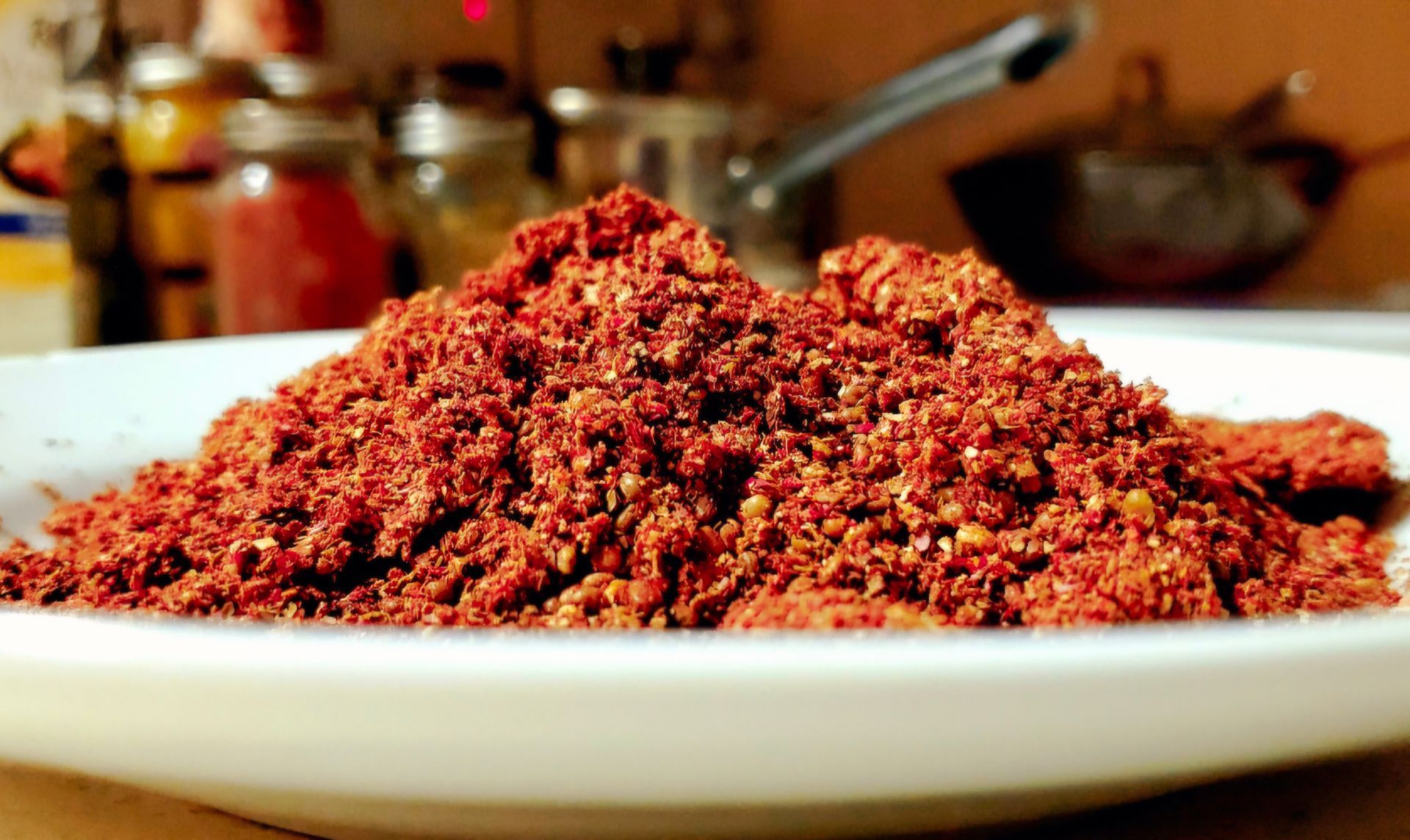 Pile of red spice powder on a white plate in a kitchen.