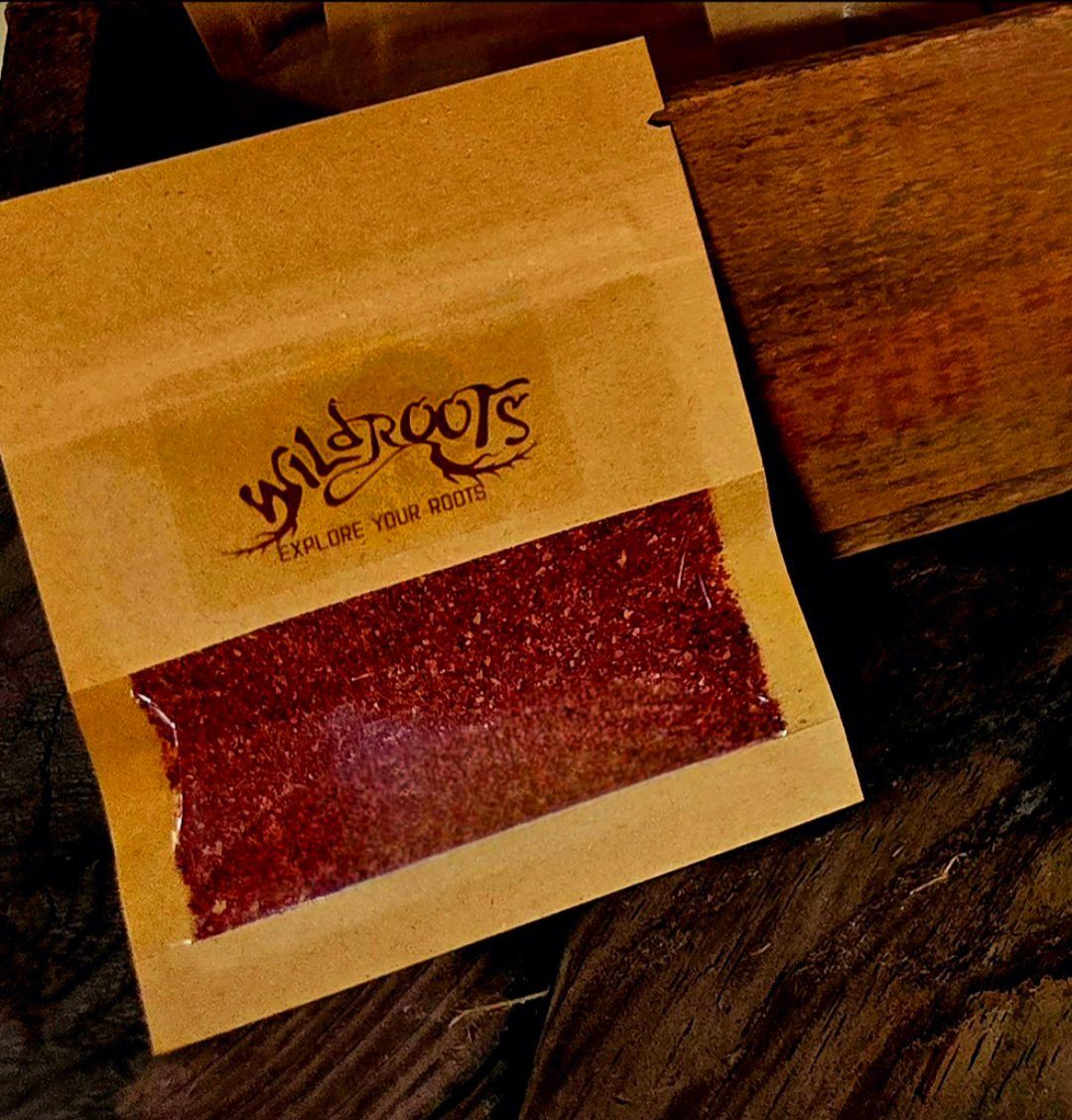 Brown paper packet with transparent window revealing red granular contents;