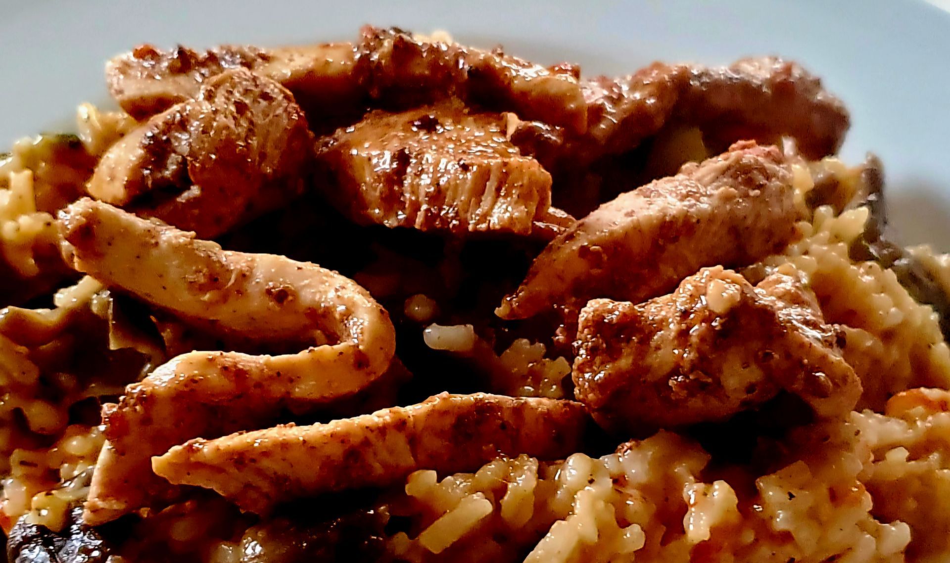 Chicken strips atop rice and vegetables, likely a savory meal.